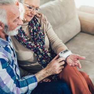 Man and Woman sitting on couch looking at wearable technology on wrist