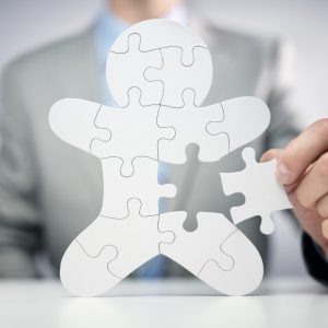 Man putting together human shaped puzzle