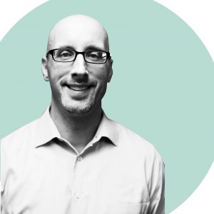 Man with glasses smiling at camera black and white with blue background