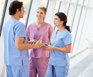 Three medical professionals talking in hallway
