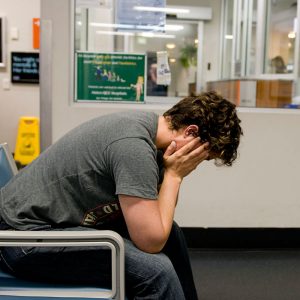 Man sitting in char with head in hands