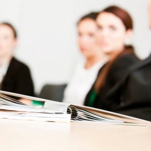 Silhouettes sitting around table with binder on surface