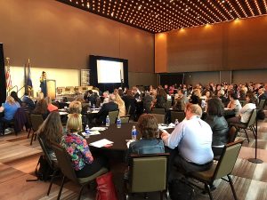 Audience sitting at round tables listening to presenter