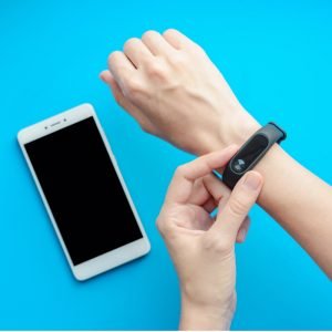 Blue background with an arm wearing technology and a phone