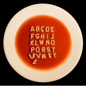 Alphabet soup in white bowl on dark background