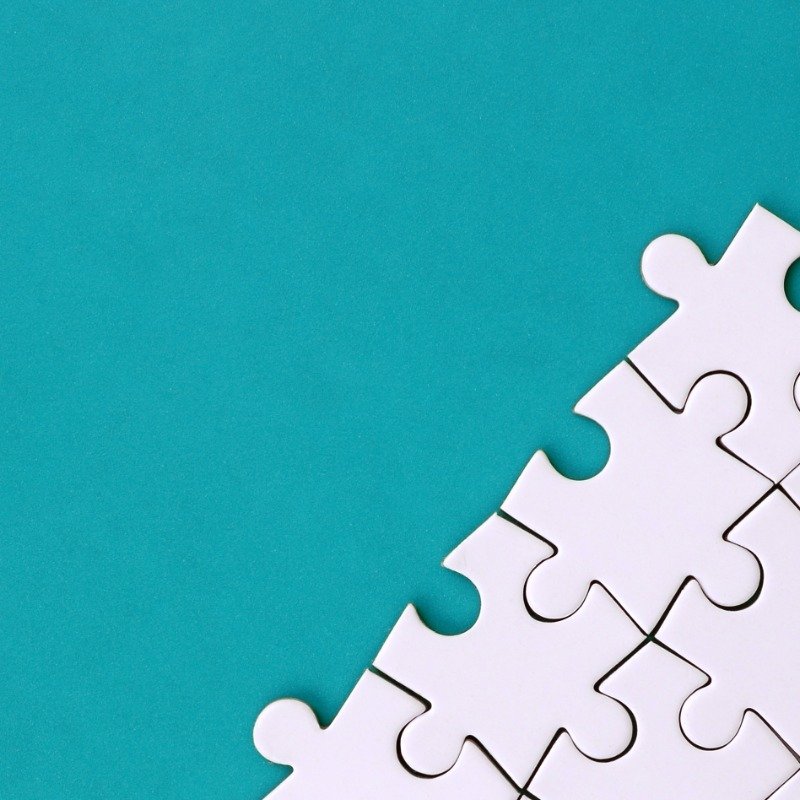 Blue-green background with white puzzle pieces in bottom right corner